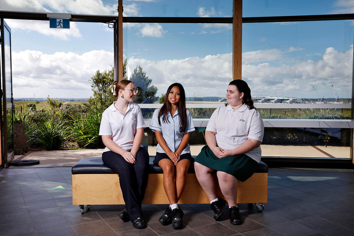 Three high school female students sitting on bench